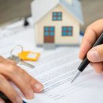 Ein Mann unterzeichnet einen Kaufvertrag für ein Haus.