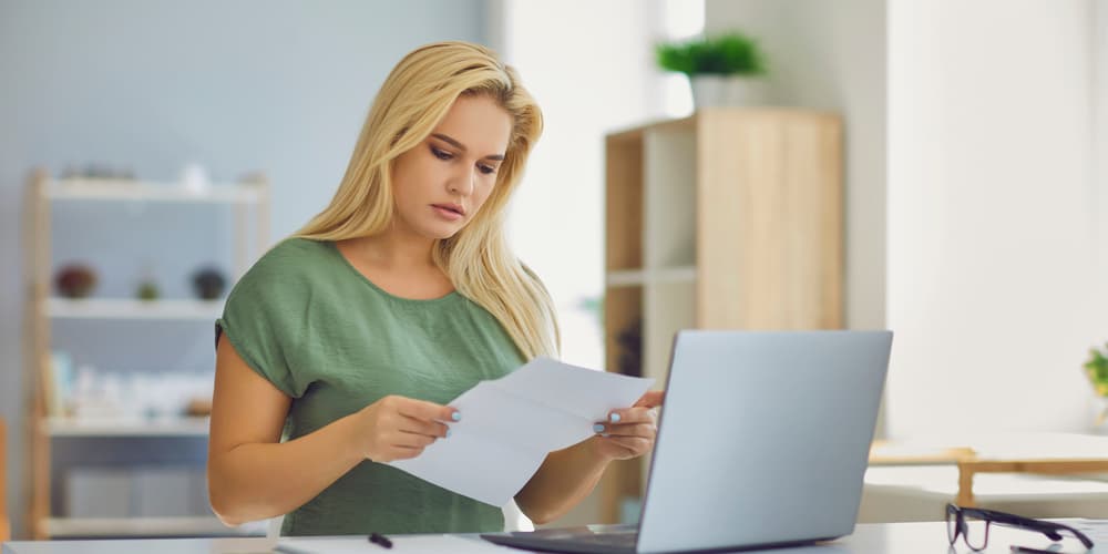 Eine Frau hält ihren Vertrag zur Baufinanzierung in der Hand, sie möchte die Baufinanzierung kündigen