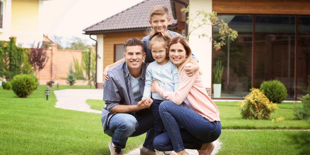 Eine Familie vor ihrem Haus, sie hat gravierendeFehler bei der Eigenheimfinanzierung vermieden