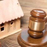 Ein Richterhammer und ein Modellhaus als Symbole für den Bestandsschutz im Baurecht