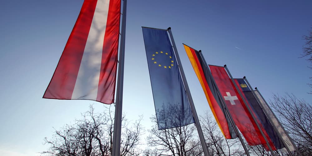 Flaggen deutschsprachiger Länder und der EU als Symbol für die Baufinanzierung für Grenzgänger