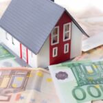 Ein Modellhaus auf Euro-Banknoten als Symbolbild für das Tilgungsparadox