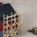 Ein Modellhaus mit einem Baugerüst als Symbol für eine notwendige Zwischenfinanzierung