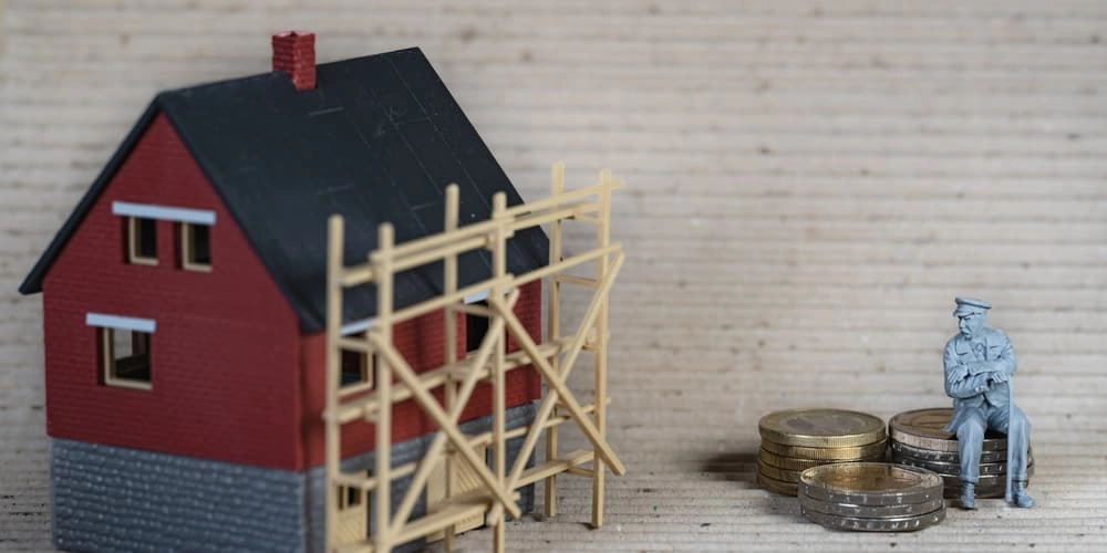 Ein Modellhaus mit einem Baugerüst als Symbol für eine notwendige Zwischenfinanzierung