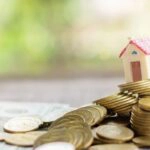 Ein Modellhaus auf Münzen als Symbol für die Wertsteigerung von Immobilien