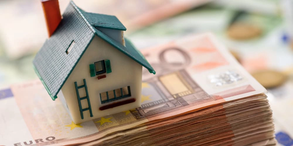 Ein Haus auf einem Geldbündel als Symbol für eine Immobilienrente