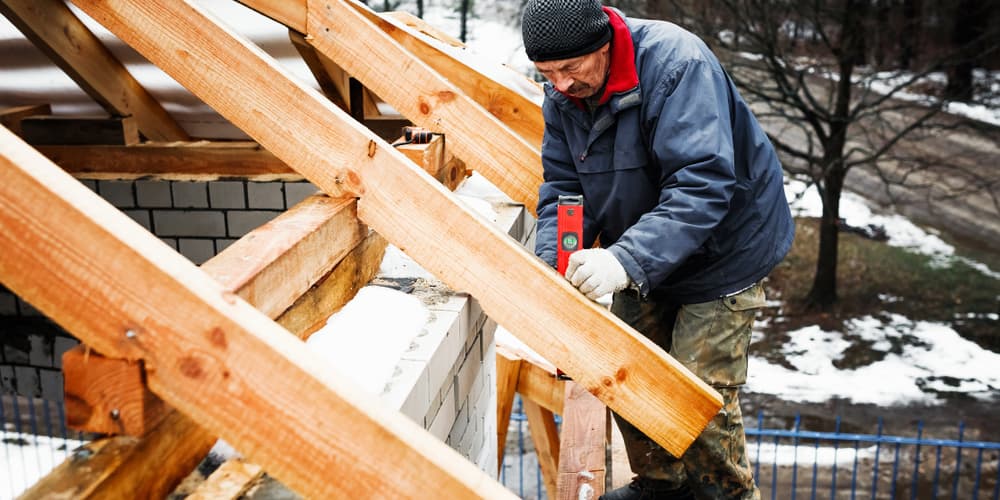 Ein Mann beim Hausbau im Winter