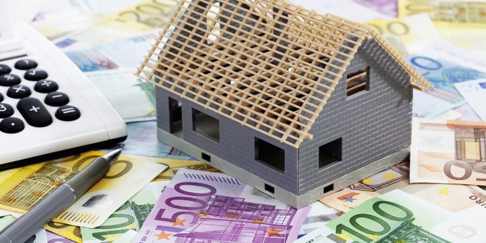 Das Modell eines Hauses auf Geldscheinen als Symbol für die Baunebenkosten
