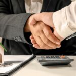 Zwei Menschen schließen per Handschlag ein Verkäuferdarlehen ab