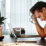 Ein Mann sitzt besorgt vor dem PC, er ist trotz Baufinanzierung arbeitslos geworden
