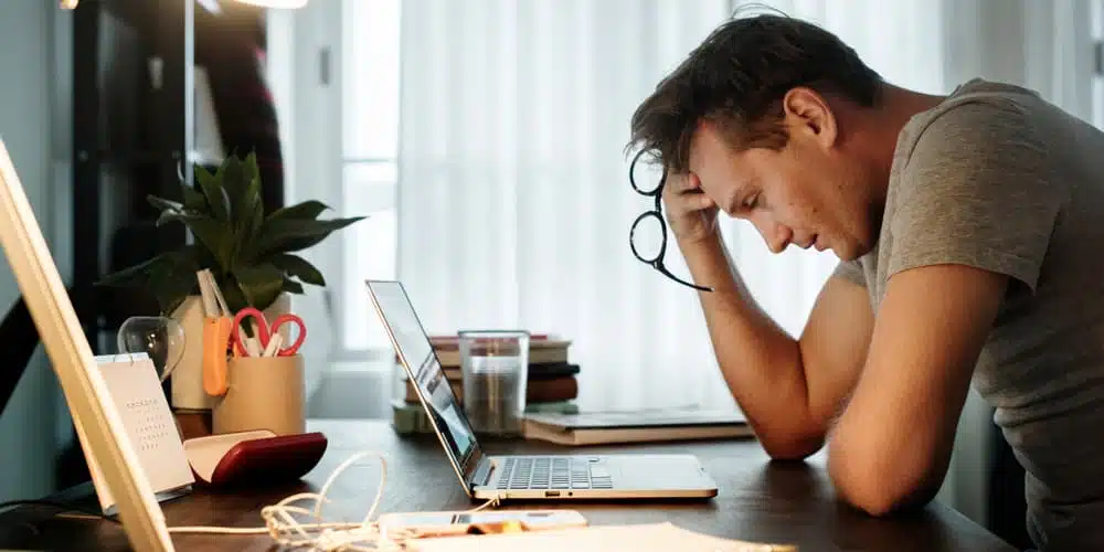 Ein Mann sitzt besorgt vor dem PC, er ist trotz Baufinanzierung arbeitslos geworden