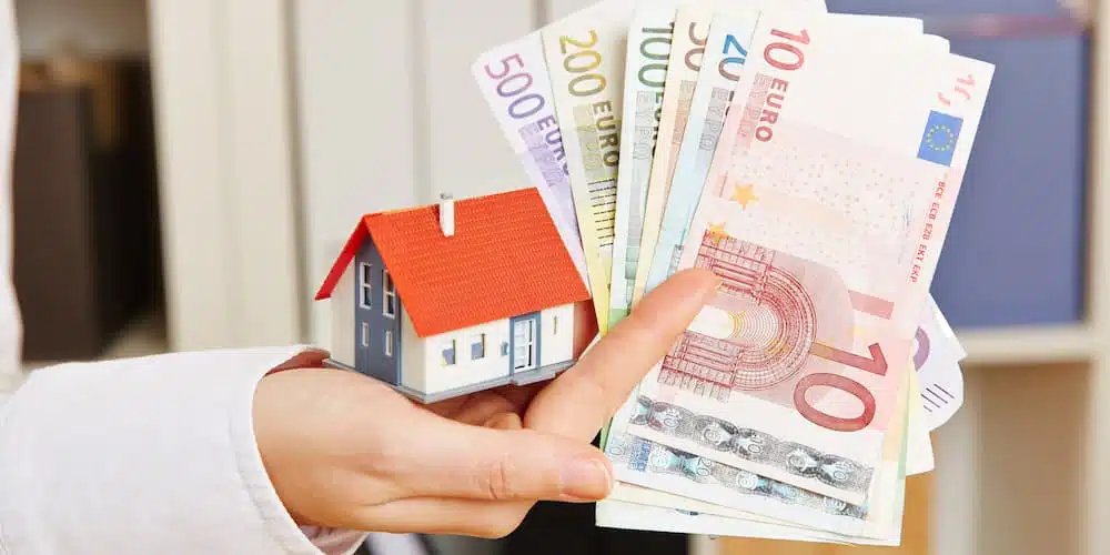 Ein Modellhaus und Geldscheine als Symbole für ein Eigentümerdarlehen