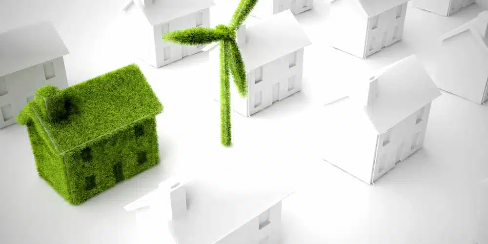 Ein grünes Modellhaus in einer Siedlung als Symbol für nachhaltiges Bauen?