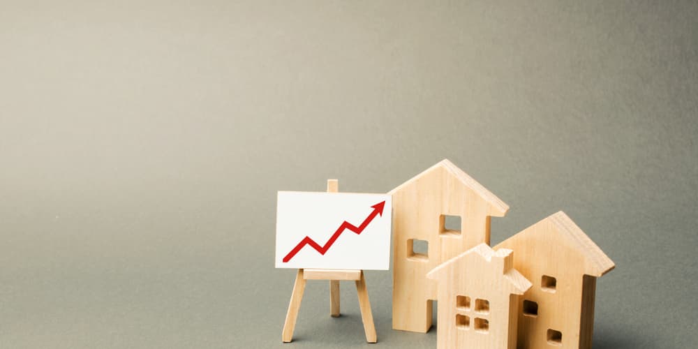 Modellhäuser und ein aufsteigender Pfeil, als Symbol für Investmentfinanzierung